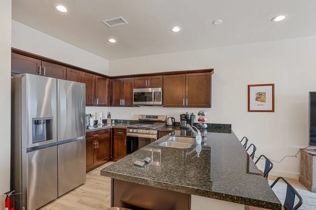 A modern, fully equipped kitchen with stainless steel appliances, a granite countertop, wood cabinets, and a central island. The space feels functional yet homely, ideal for preparing a fresh cup of coffee or a quick meal between work sessions or outdoor activities.