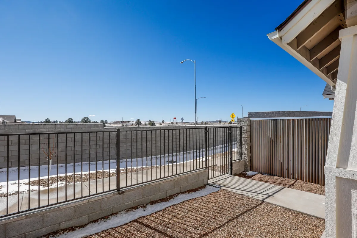An exterior shot of a tranquil backyard with a fence and pathway beneath a broad, open sky. The setting is serene, ideal for outdoor relaxation or stargazing under Flagstaff's famous dark skies.
